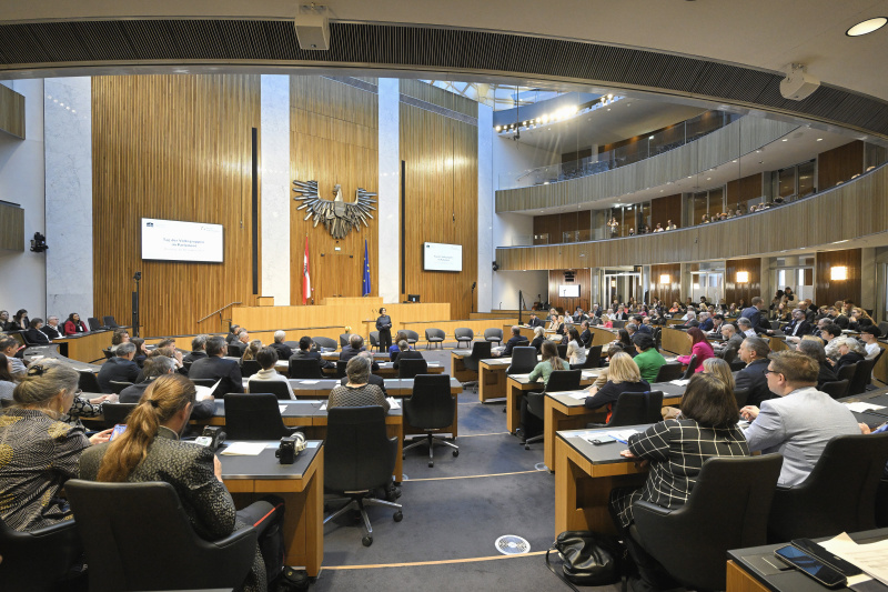 Moderation Katja Gasser. Blick Richtung Veranstaltungsteilnehmer:innen