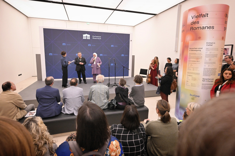 Von links: Moderation Katja Gasser, Vorsitzender des Volksgruppenbeirates der Volksgruppe der Roma Emmerich Gärtner-Horvath, Muttersprachenlehrerin Romanes Rabie Peric. Blick Richtung Veranstaltungsteilnehmer:innen