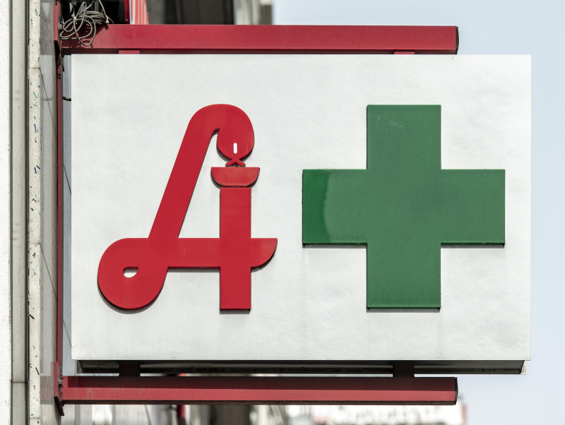 Schild einer Apotheke mit Äskulap Symbol und grünem Kreuz Symbol