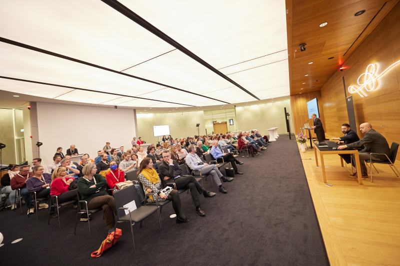 Eröffnungsworte Parlamentsdirektor Harald Dossi am Rednerpult. Blick Richutng Veranstaltungsteilnehmer:innen