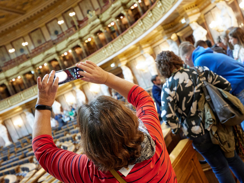 Eine Führungs-Teilnehmerin nimmt mit ihrem Smartphone ein Foto vom historischen Sitzungssaal auf.