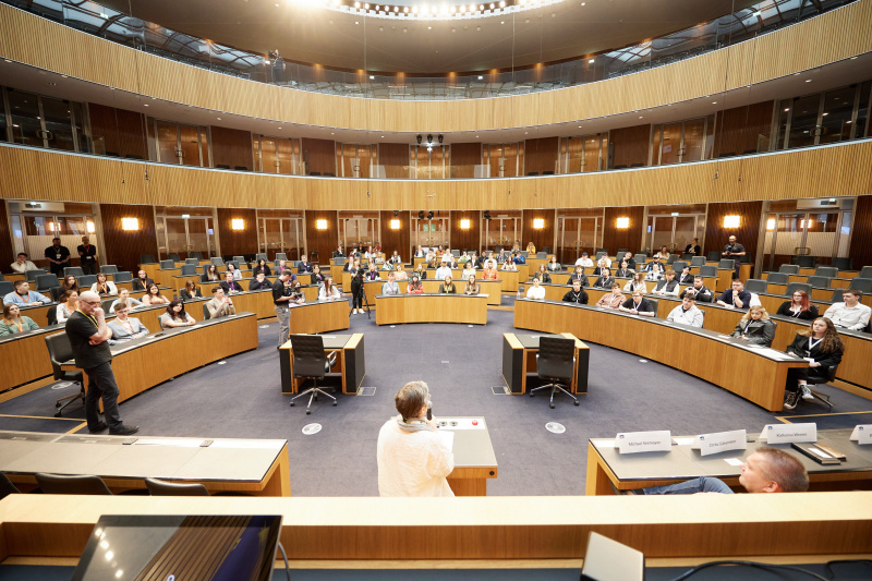 Moderation Karoline Iber. Blick Richtung Veranstaltungsteilnehmer:innen