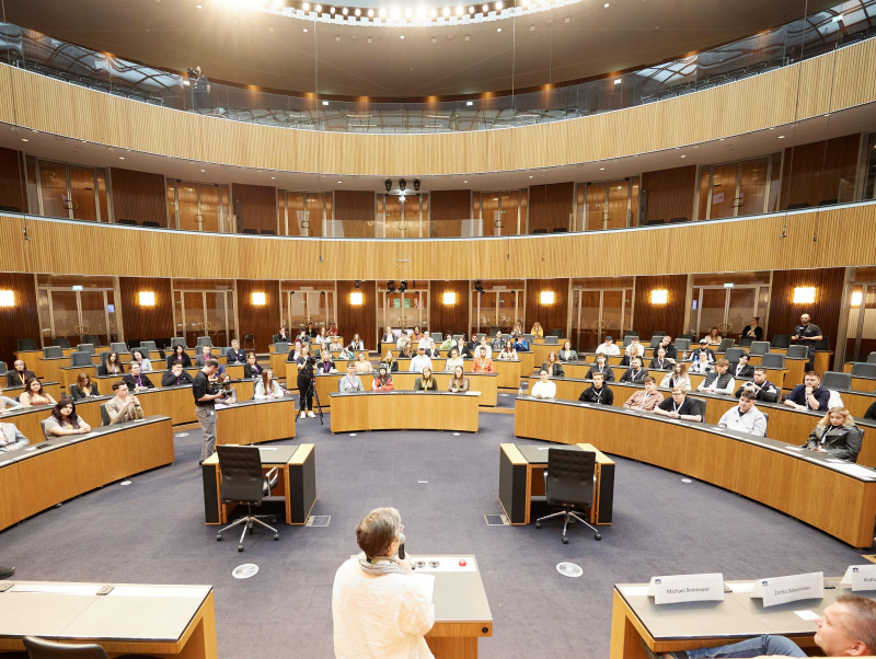 Moderation Karoline Iber. Blick Richtung Veranstaltungsteilnehmer:innen