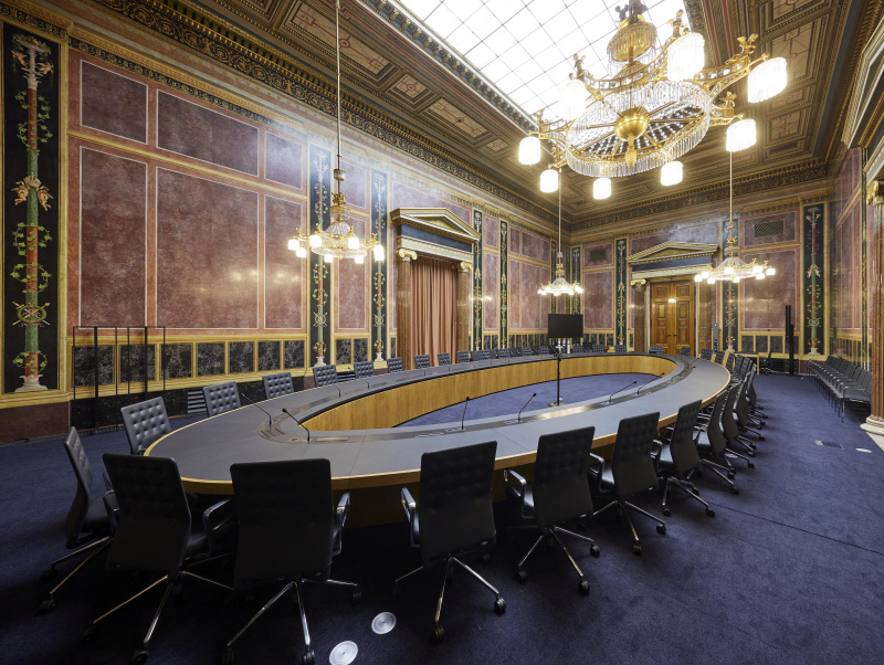 Großer ovaler Tisch für Sitzungen im Lokal 5 mit reich verzierten Wände und großen Lustern. 