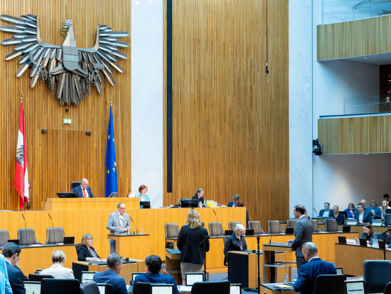 Anfragebeantwortung durch Gesundheitsminister Johannes Rauch (GRÜNE) am Redner:innenpult. Blick Richtung Sitzungsteilnehmer:innen