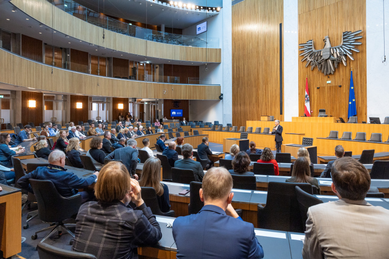 Begrüßungsworte von Parlamentsdirektor Harald Dossi. Blick Richtung Veranstaltungsteilnehmer:innen