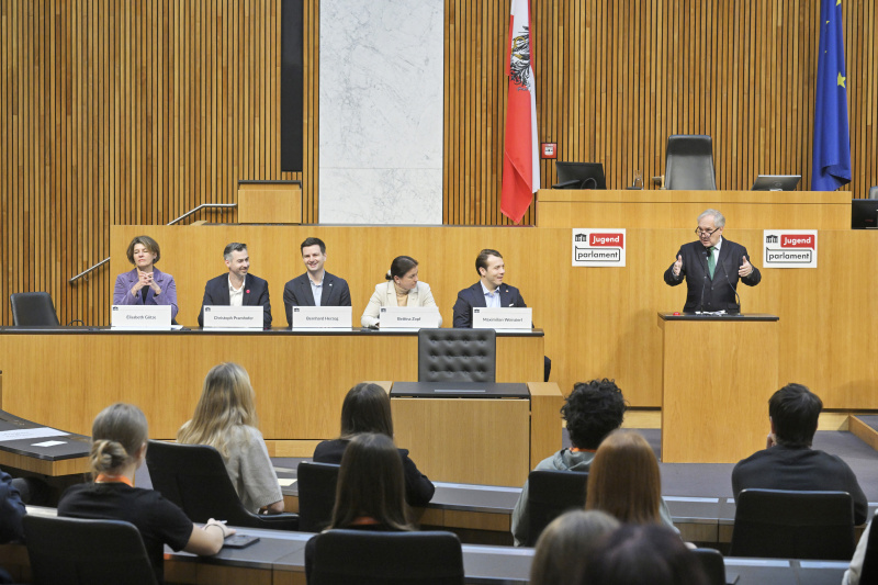 Begrüßung durch  Nationalratspräsident Walter Rosenkranz (FPÖ) am Rednerpult. Regierungsbank von links: Nationalratsabgeordneter Elisabeth Götze (GRÜNE), Nationalratsabgeordneter Christoph Pramhofer (NEOS), Nationalratsabgeordneter Bernhard Herzog (SPÖ), Nationalratsabgeordnete Bettina Zopf (ÖVP), Nationalratsabgeordneter Maximilian Weinzierl (FPÖ)