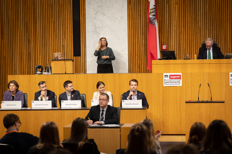 Nationalratspräsident Walter Rosenkranz (FPÖ) am Präsidium. Regierungsbank von links: Nationalratsabgeordneter Elisabeth Götze (GRÜNE), Nationalratsabgeordneter Christoph Pramhofer (NEOS), Nationalratsabgeordneter Bernhard Herzog (SPÖ), Nationalratsabgeordnete Bettina Zopf (ÖVP), Nationalratsabgeordneter Maximilian Weinzierl (FPÖ)