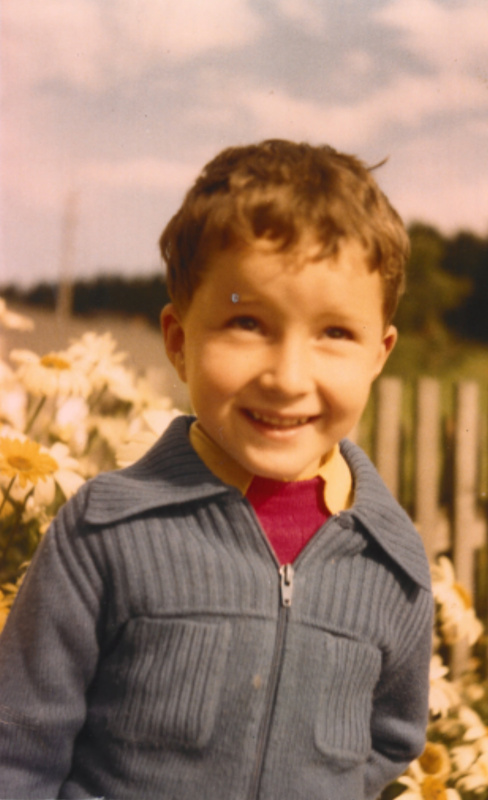 Albert Royer als kleiner Bursch im Garten vor Blumen