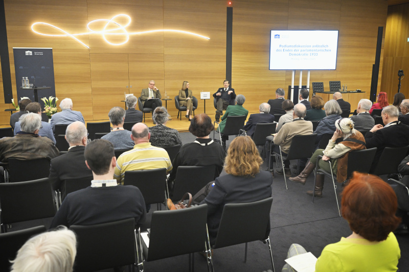 Podiumsdiskussion. Von links: Professor für Rechts- und Verfassungsgeschichte i.R., Universität Wien Thomas Simon, Moderatorin Mariella Gittler, Professor für neuere Geschichte i.R., Universität Wien.Lothar Höbelt. Blick Richtung Veranstaltungsteilnehmer:innen
