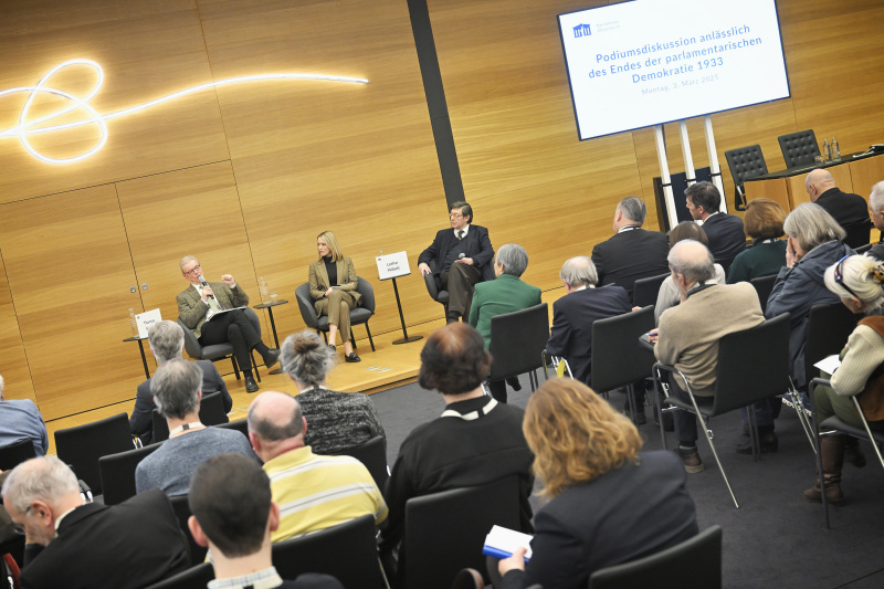 Podiumsdiskussion. Von links: Professor für Rechts- und Verfassungsgeschichte i.R., Universität Wien Thomas Simon, Moderatorin Mariella Gittler, Professor für neuere Geschichte i.R., Universität Wien.Lothar Höbelt. Blick Richtung Veranstaltungsteilnehmer:innen