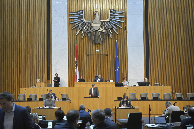 Am Redner:innenpult: Nationalratsabgeordneter Veit Dengler (NEOS). Blick Richtung Sitzungsteilnehmer:innen