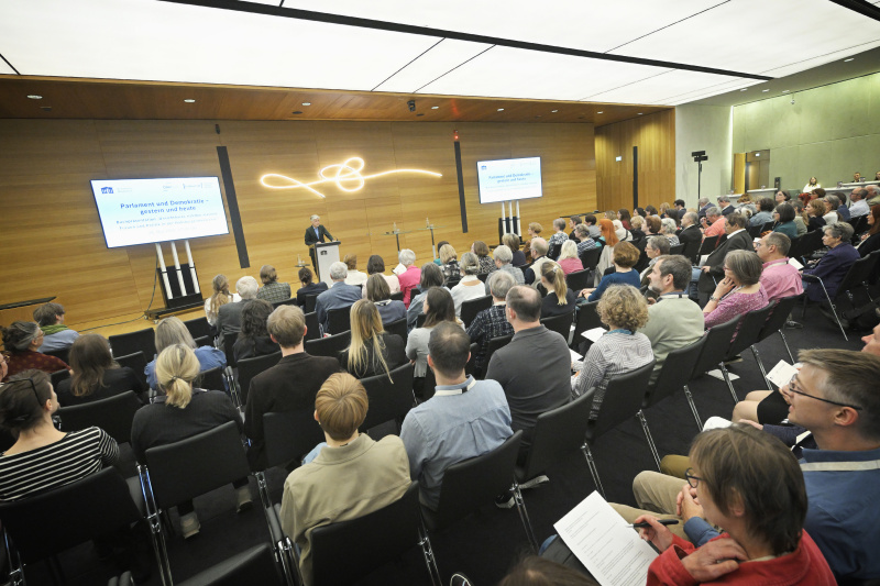Eröffnungsworte. Parlamentsdirektor Harald Dossi. Blick Richtung Veranstaltungsteilnehmer:innen