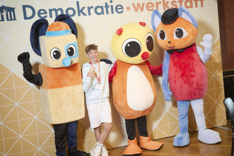 Schüler:innen mit den Maskottchen der Demokratiewerkstatt