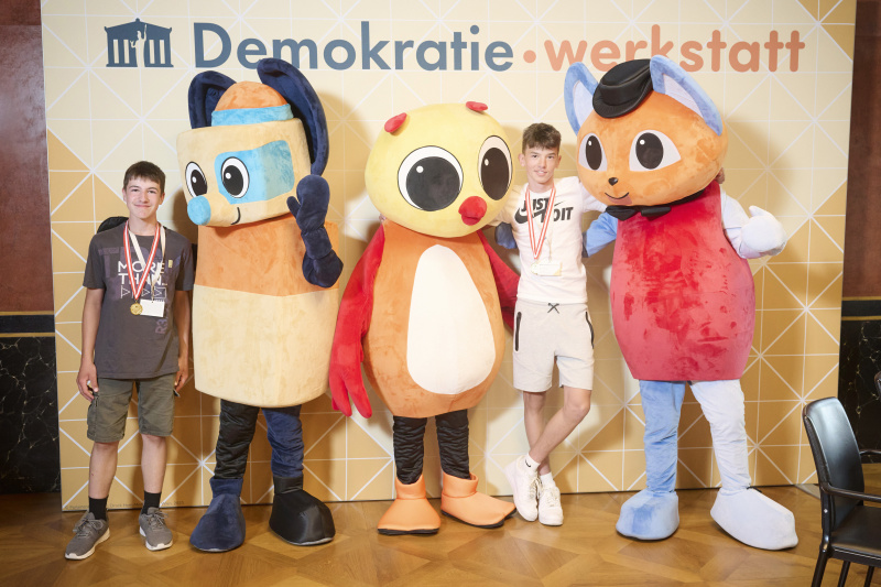 Schüler:innen mit den Maskottchen der Demokratiewerkstatt