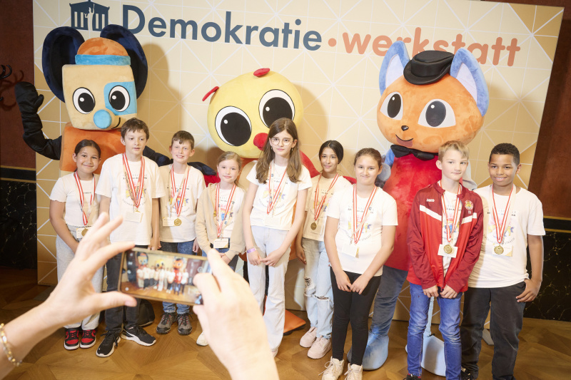 Schüler:innen mit den Maskottchen der Demokratiewerkstatt