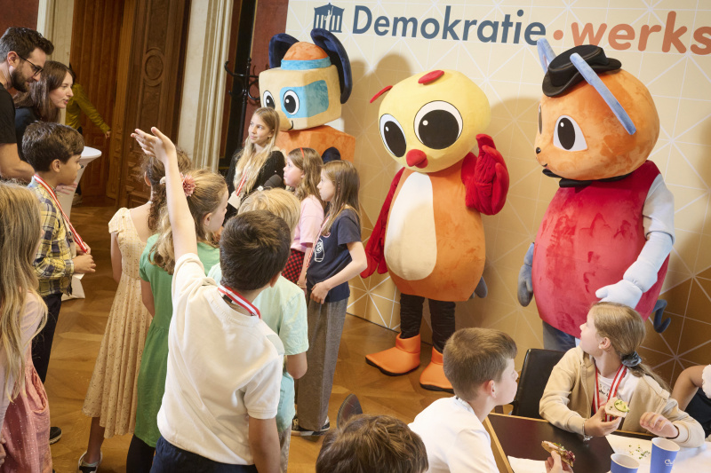 Schüler:innen mit den Maskottchen der Demokratiewerkstatt
