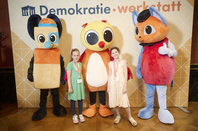 Schüler:innen mit den Maskottchen der Demokratiewerkstatt