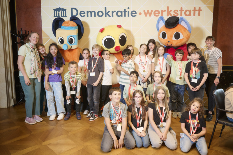 Schüler:innen mit den Maskottchen der Demokratiewerkstatt