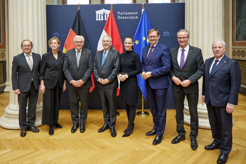 Fahnenfoto. 1. von links: Zweiter Nationalratspräsident Peter Haubner (ÖVP), 3. von links:  Bundespräsident der Bundesrepublik Deutschland Frank Walter Steinmeier, 4. Von links: Nationalratspräsident Walter Rosenkranz (FPÖ), 5. von links: Nationalratsabgeordnete Lisa Schuch-Gubik (FPÖ), 6. von links: Nationalratsabgeordneter Rudolf Silvan (SPÖ)