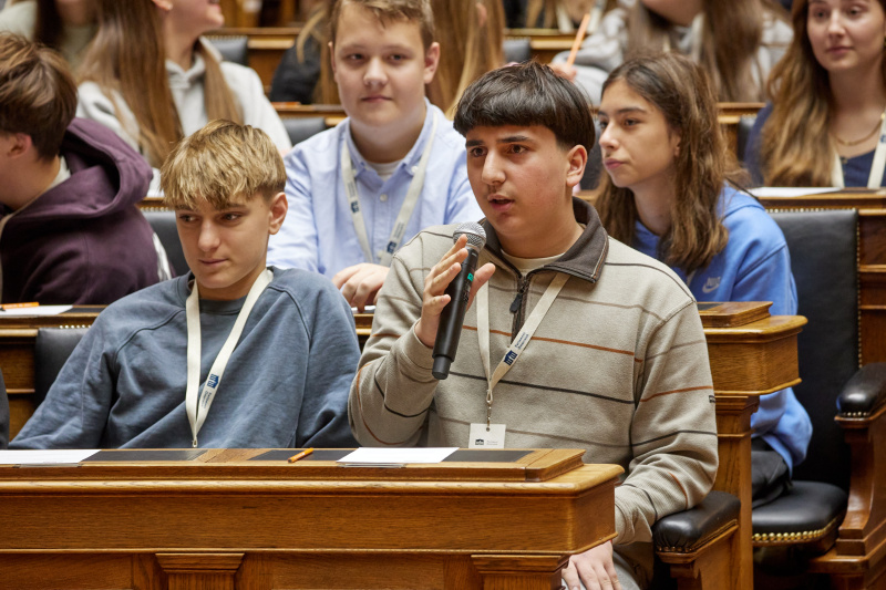 Blick Richtung Schülerinnen und Schüler. Wortmeldung eines Schülers