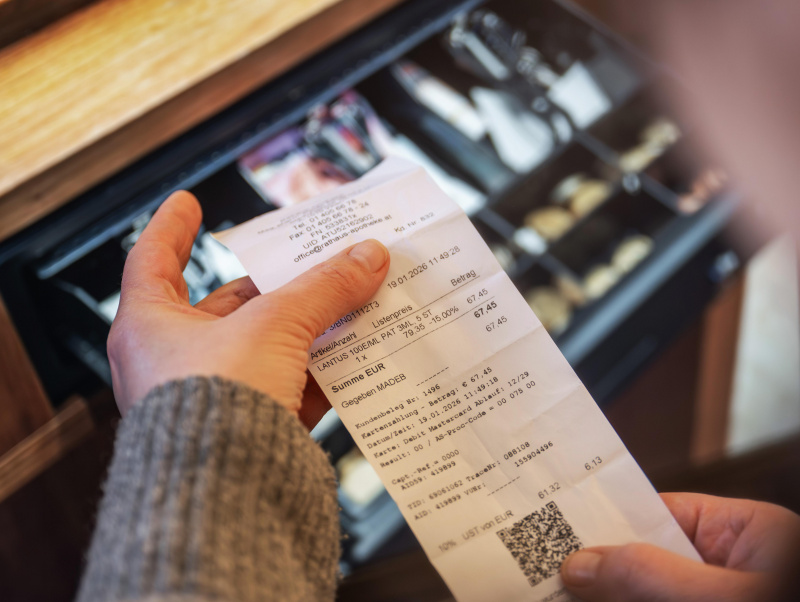 Beleg / Kassenzettel vor geöffneter Geldlade einer Registrierkassa