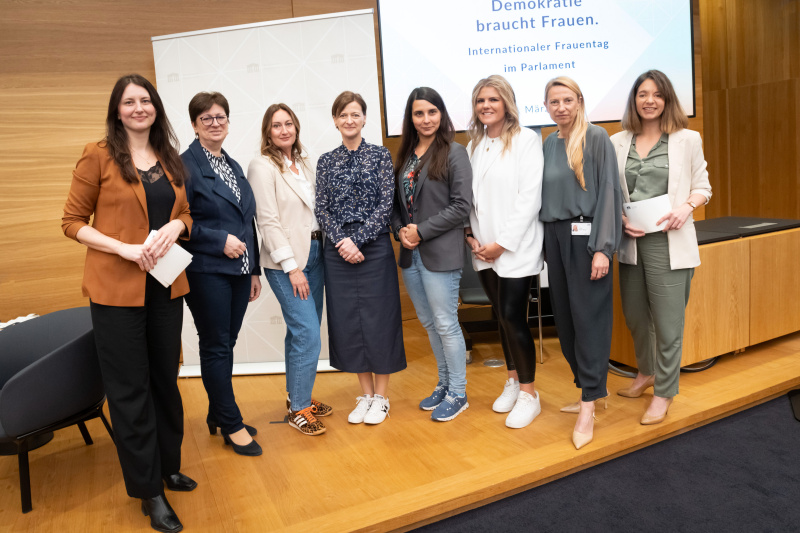 Gruppenfoto Podium. Von links: Stv. Teamleiterin Newsroom Amra Duric-Müller, Nationalratsabgeordnete und Frauensprecherin Rosa Ecker (FPÖ), Nationalratsabgeordnete und Frauensprecherin Sabine Schatz (SPÖ), Nationalratsabgeordnete und Frauensprecherin Meri Disoski (GRÜNE),Nationalratsabgeordnete und Frauensprecherin Lisa Aldali (NEOS), Nationalratsabgeordnete und Frauensprecherin Juliane Bogner-Strauß (ÖVP), Gleichbehandlungsbeauftragte Valerie Watzek