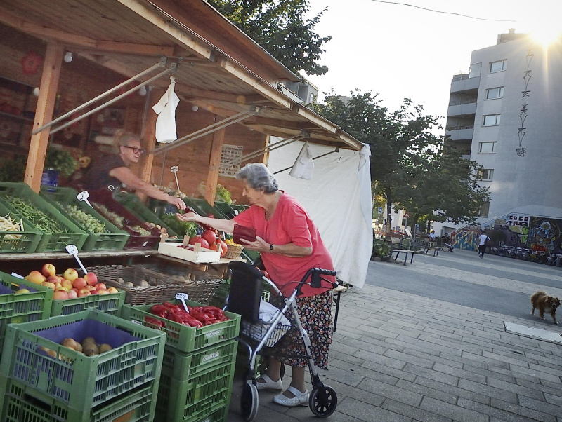 Pensionistin mit Rollator bezahlt bei einem Marktstand