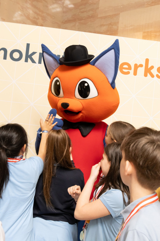 Maskottchen der Demokratiewerkstatt mit Schülerinnen und Schülern am Fotopoint in der Säulenhalle
