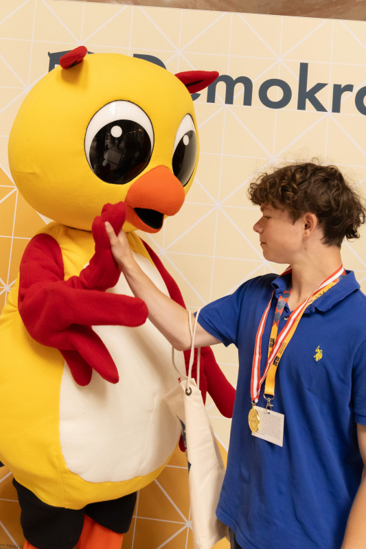 Maskottchen der Demokratiewerkstatt mit Schülerinnen und Schülern am Fotopoint in der Säulenhalle