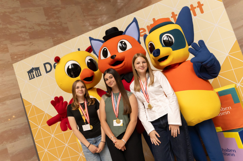 Maskottchen der Demokratiewerkstatt mit Schülerinnen und Schülern am Fotopoint in der Säulenhalle