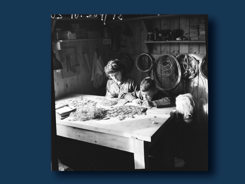 In Kremsmünster untergebrachte Vertriebene aus dem nordböhmischen Gablonz/Jablonec nad Nisou bei der Heimarbeit in der Glasperlenkettenerzeugung, 1952