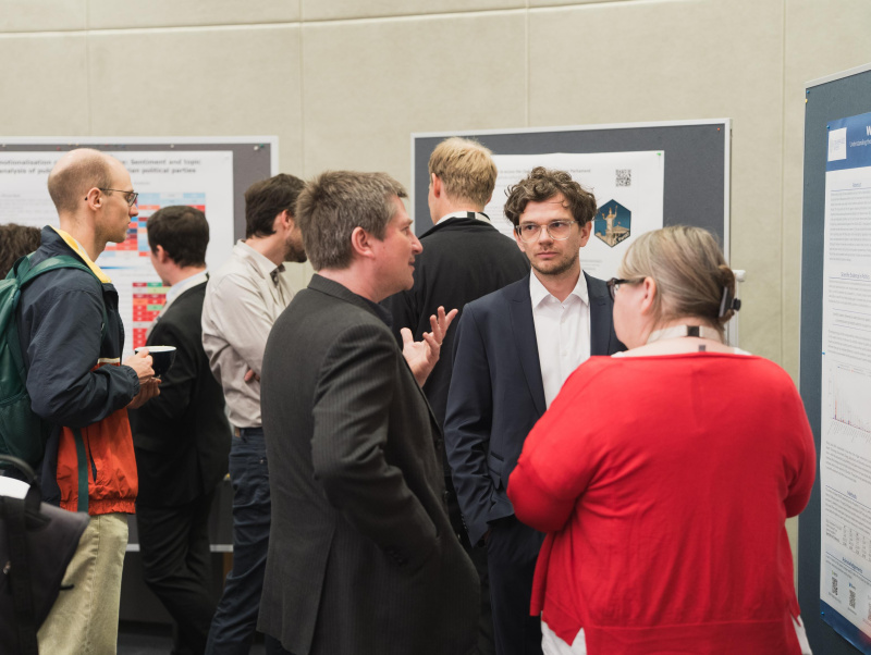 Teilnehmende an der Postersession, die mit den Autoren der Poster diskutieren