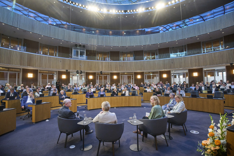 Podiumsgespräch. Blick Richtung Veranstaltungsteilnehmerinnen und -teilnehmer