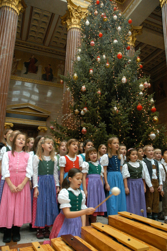 Der Kinderchor singt vor dem Weihnachtsbaum.