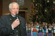 der Bürgermeister von Liezen Rudolf Hakel am Mikrofon, im Hintergrund der Kinderchor vor dem Weihnachtsbaum.