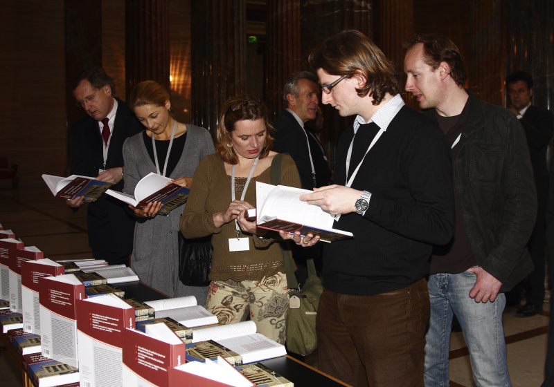 Veranstaltungsteilnehmer blättern am Bücherstand das "Wörterbuch der politischen Sprache in Österreich" durch.