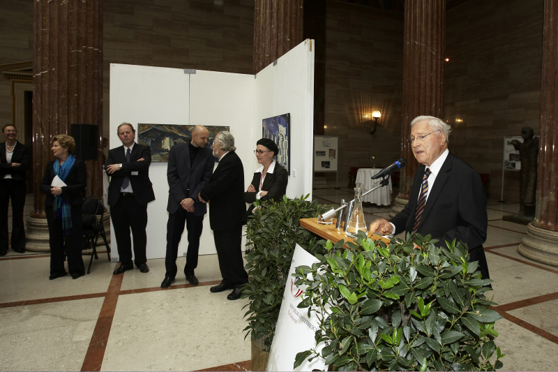 Helmut Kritzinger am Rednerpult - im Hintergrund v.li. Bürgermeisterin und Kulturreferentin der Landeshauptstadt Innsbruck Hilde Zach, ein Veranstaltungsteilnehmer, Kurator Hannes Niederlechner, Künstler Herbert Danler, Künstlerin Martina Gasser.
