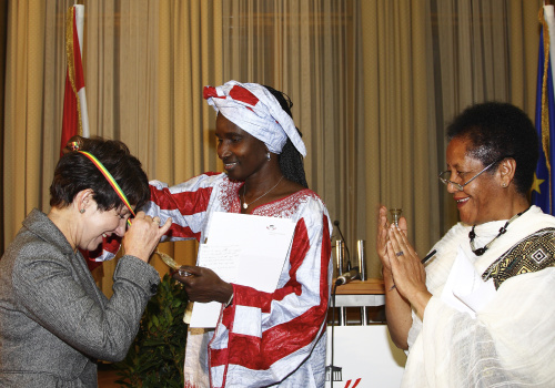 v.li. Barbara Prammer erhält eine Medaille von der Präsidentin des EURONET FGM Netzwerkes Khady Koita. Die österreichische FGM Koordinatorin im EU Daphne Projekt Etenesh Hadis applaudiert.
