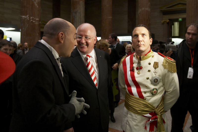 Kaiser Robert Heinrich I - (Robert Palfrader) (rechts )stattet der Ausstellung einen Besuch ab, durch die Saeulenhalle gefuehrt von Univ.Prof.Dr. Stefan Karner in der Mitte und Diener Seyffenstein - (Rudi Roubinek)  (links)