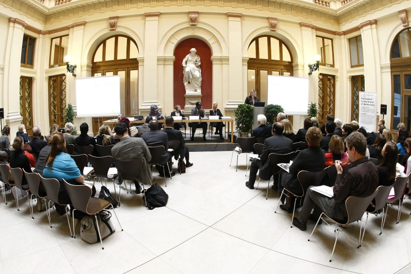Blick in Richtung Veranstaltungsteilnehmer, am Podium v.li. Lediana Mafuru, Chair HIV/AIDS Committee Tanzania, Moderatorin der Veranstaltung Maria Jonas, Philip Okundi, Executive Director Centre for Poverty Reduction and Support for Women and Orphans (CPRWO), Former Chairman OVC Committee Kenya, Chairperson of the Communications Commission in Kenya und Henriette Ahrens, UNICEF Headquarters (HIV AIDS section), Senior Advisor for Public Alliances and Resource Mobilization, am Rednerpult v.li. Nadia Rozendaal, Director Policy Advocacy, International Aids Vaccine Initiative (IAVI).