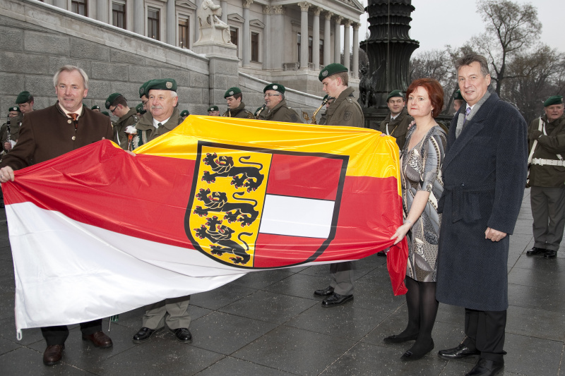 v.li. Gerhard Doerfler - Landeshauptmann von Kaernten, Dirigent der Militaermusikkapelle Kaernten , Dr. Susanne Bachmann - Parlamentsdirektion und Komm.Rat Peter Mitterer-Praesident des Bundesrates mit der Fahne Kaerntens