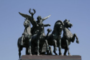 Die Quadriga ist ein Gespann, das von vier Pferden gezogen und von der Siegesgöttin Nike gelenkt wird. Sie symbolisiert den Triumpf der parlamentarischen Aktivitäten.