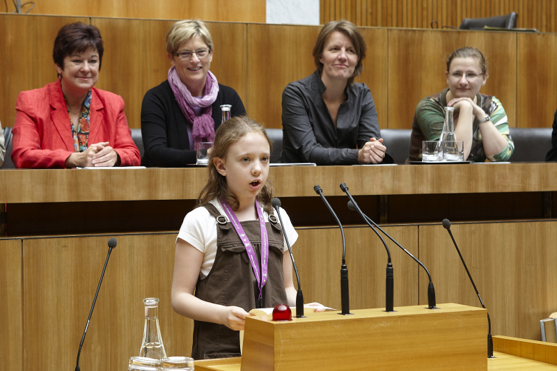 Ein junger Demokratiewerkstatt Profi bei der Ansprache am Rednerpult. Am Podium v. li.: Mag.Susanne Neuwirth - Vizepräsidentin des Bundesrates, Ursula Haubner - Nationalratsabgeordnete, Daniela Musiol - Nationalratsabgeordnete und Veranstaltungsteilnehmerin.