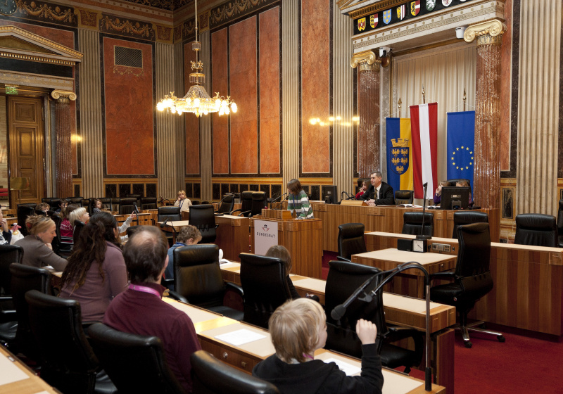 Schüler am Rednerpult. Im Hintergrund Martin Preineder - Präsident des Bundesrates mit SchülerInnen.