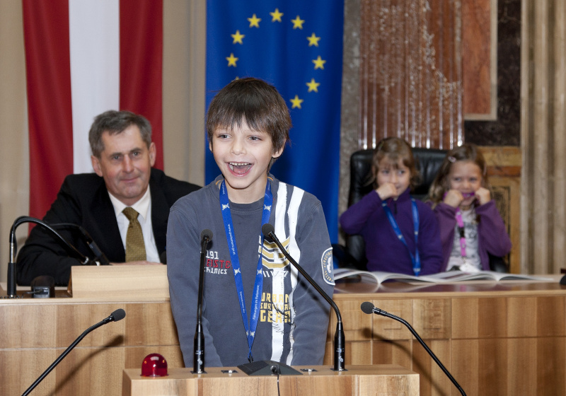 Schüler am Rednerpult. Im Hintergrund Martin Preineder - Präsident des Bundesrates mit SchülerInnen.