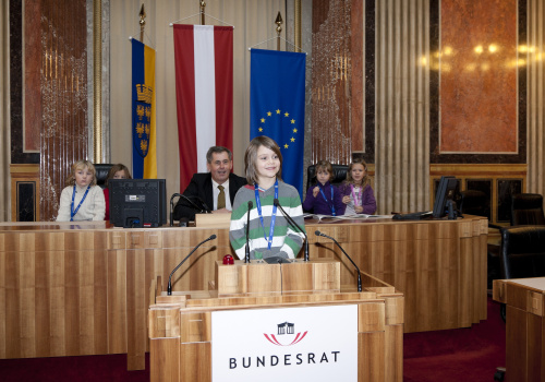 Schüler am Rednerpult. Im Hintergrund Martin Preineder - Präsident des Bundesrates mit SchülerInnen.