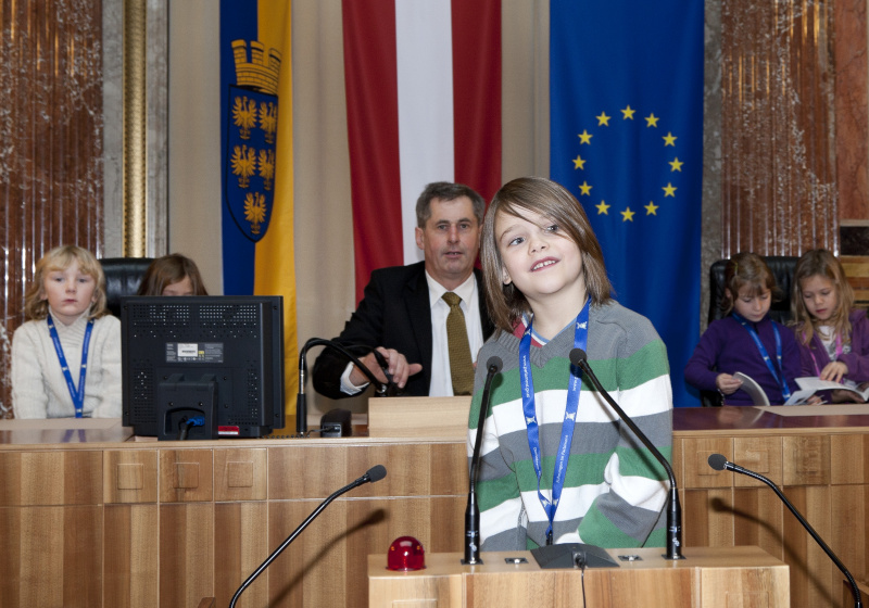 Schüler am Rednerpult. Im Hintergrund Martin Preineder - Präsident des Bundesrates mit SchülerInnen.
