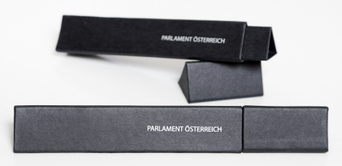 Dreieckige Geschenkverpackung aus Karton, schwarz mit Schriftzug Parlament Österreich in silber