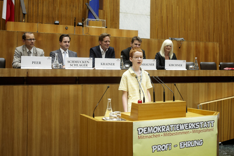 Schüler der zum Demokratiewerkstatt-Profi geehrt wird hält eine kurze Rede. Im Hintergrund auf der Regierungsbank v. li.: Mag. Bernhard Peer, Johannes Schmuckenschlager - Abgeordneter zum Nationalrat, Kai Jan Krainer - Abgeordneter zum Nationalrat, Mag. Albert Steinhauser - Abgeordneter zum Nationalrat und Elke Kirchner - Klub der Freiheitlichen